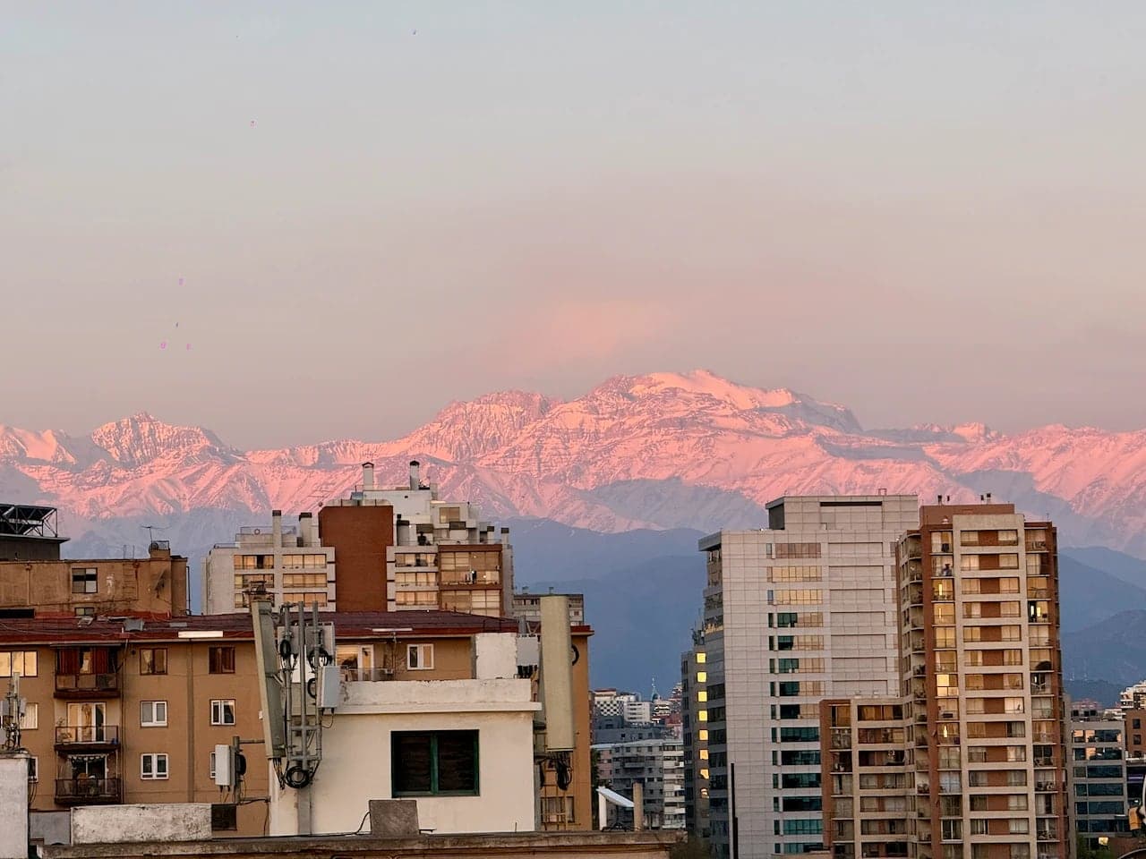 The Andes lit pink at dusk behind apartment towers in Santiago